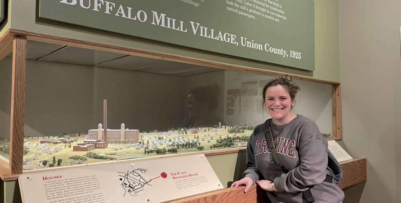 Sharon George, Next To A Diorama Of The Buffalo Mill Village At The South Carolina State Museum