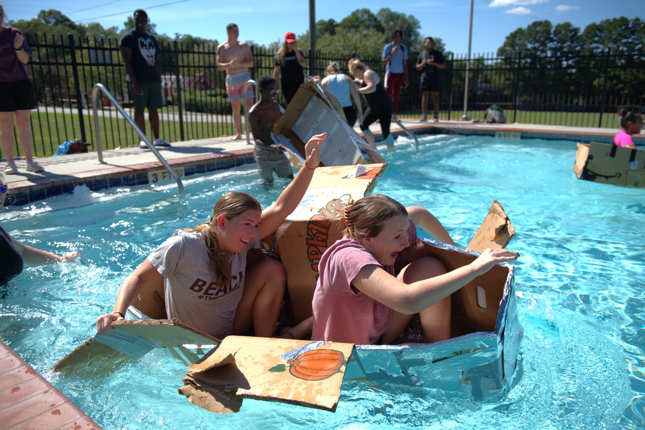 Students in cardboard boats in the swimming pool