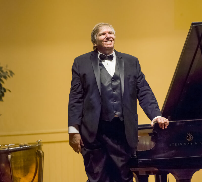 Mac Frampton stands by a piano in Memorial Hall